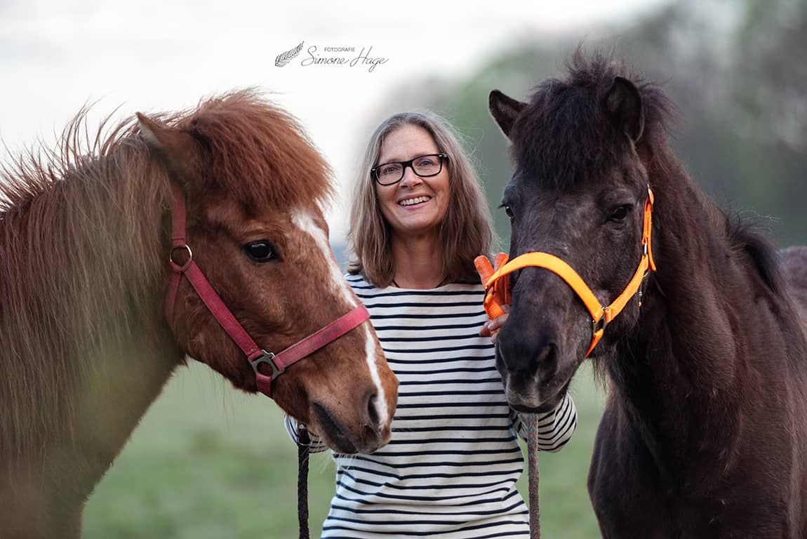 Kellina Klein zwischen zwei Pferden in der Natur